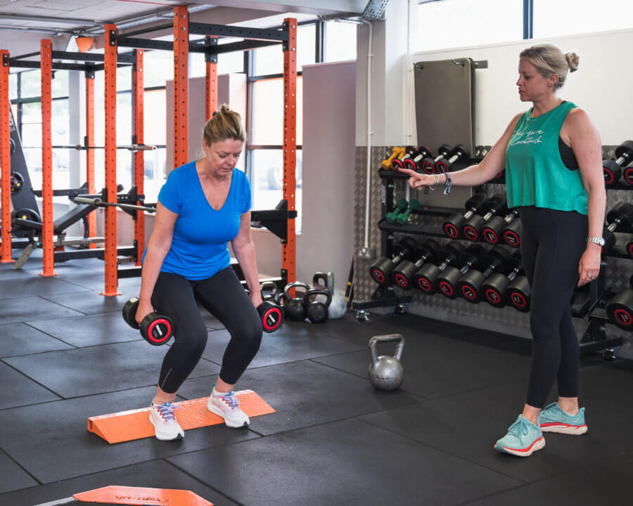 Helen A training a client with dumbbell squats